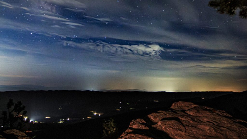 View of a starry night sky from a rock overlook.a